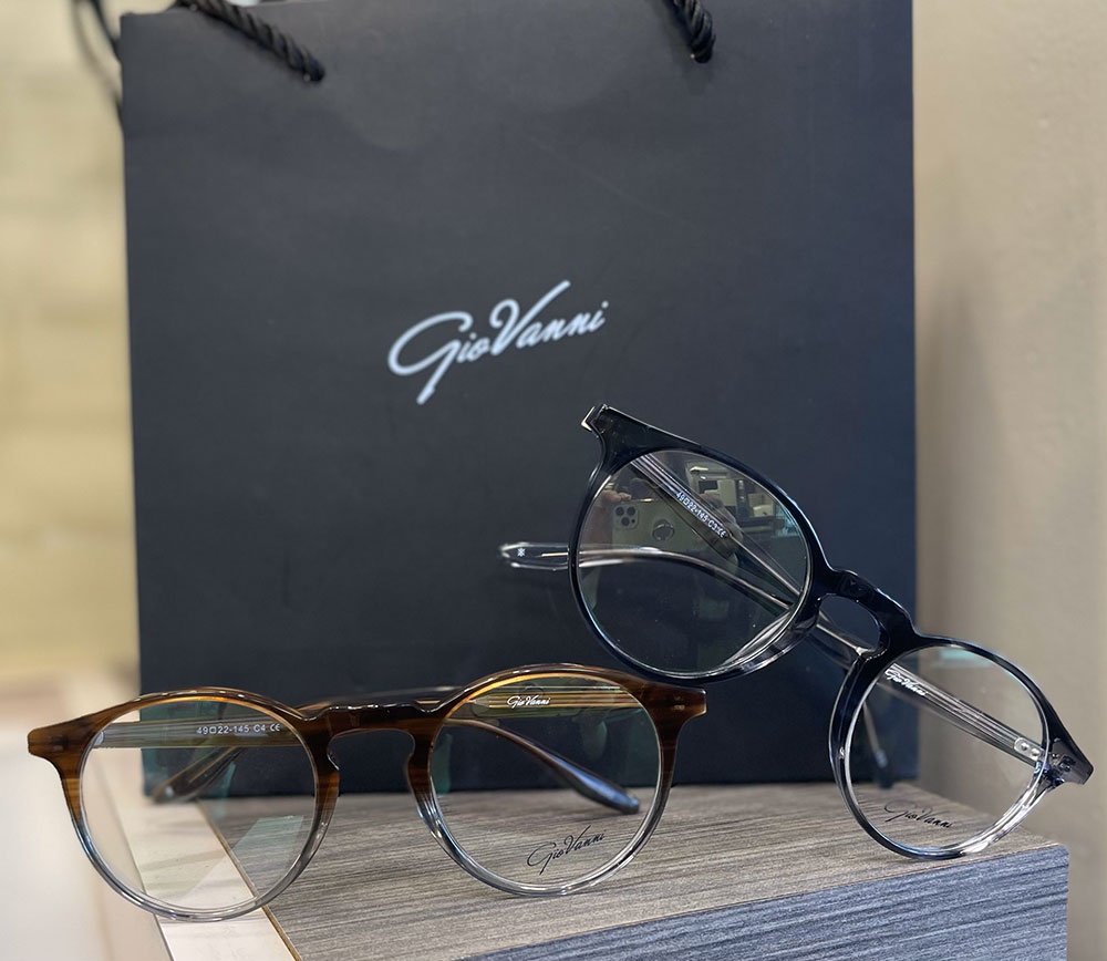 Eyeglasses displayed on a table, with a brand logo visible in the background.