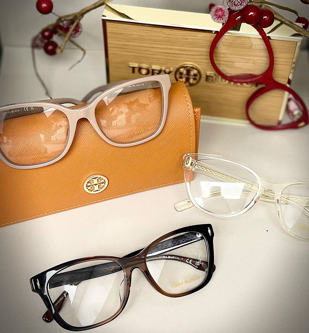 A collection of eyeglasses and a handbag with the brand 'Tory Burch' displayed on a white surface.