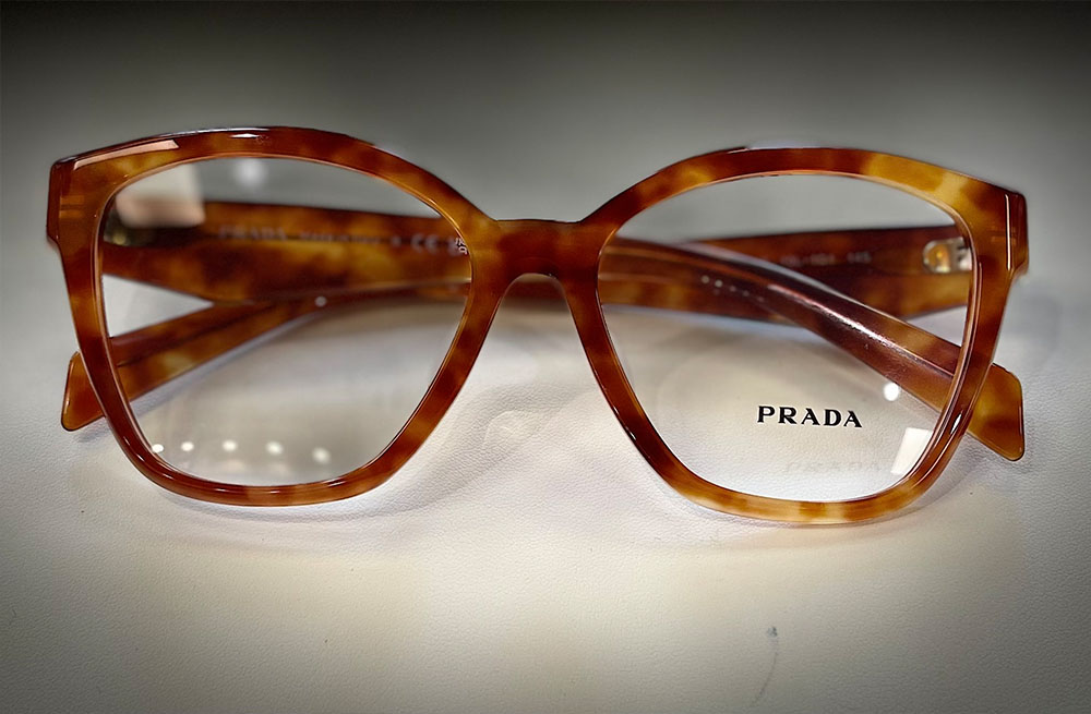 Elegant tortoiseshell glasses with a distinctive metal frame, showcasing the iconic Prada logo.