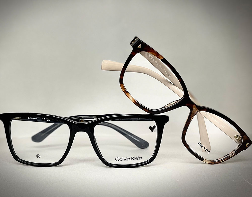 A photograph of a pair of black glasses with clear lenses, accompanied by an identical pair of glasses with brown tortoiseshell temples.