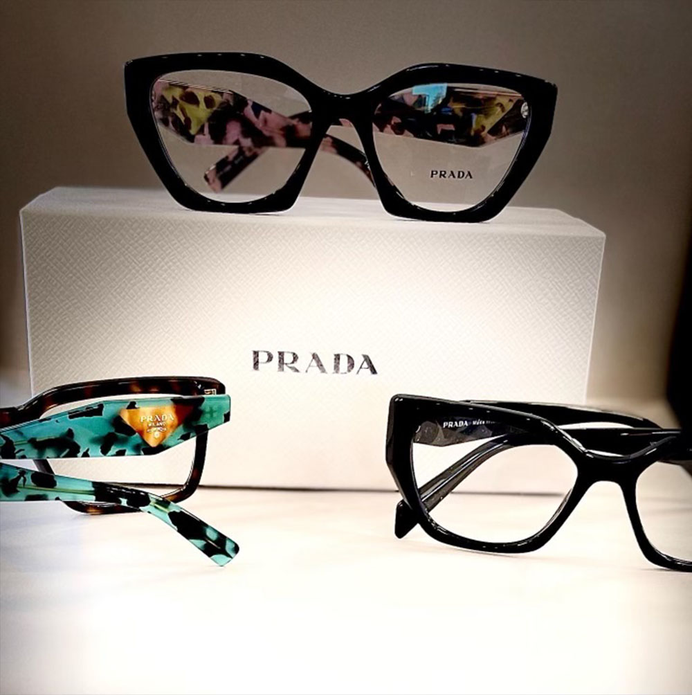 Three pairs of fashionable glasses with floral and geometric patterns, displayed in a box against a white background.
