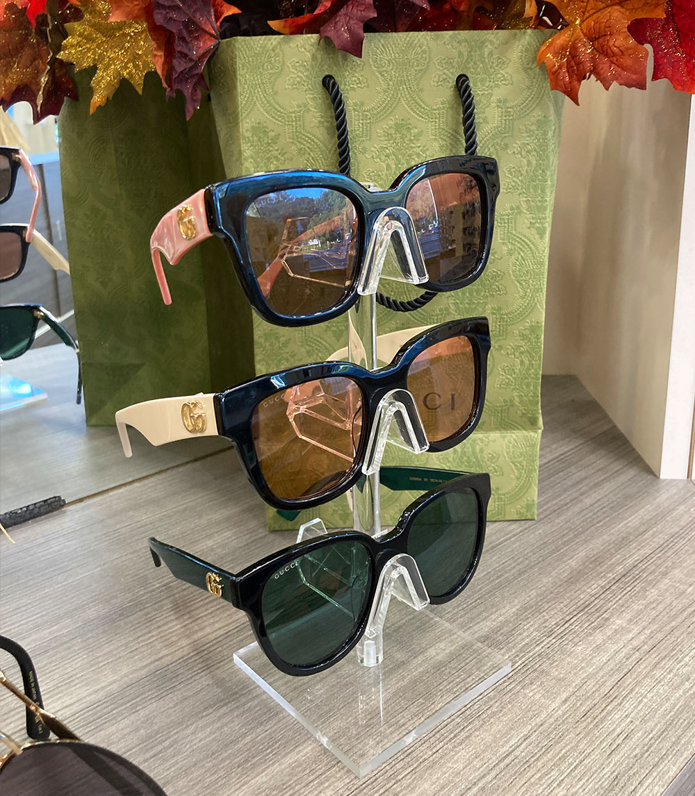 The image displays a collection of sunglasses with different frame colors and styles, presented on a display stand.