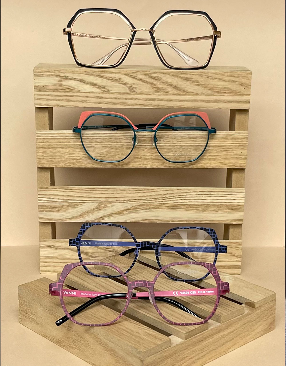 The image showcases a collection of eyeglasses displayed on a wooden crate, with different styles and colors visible.