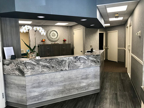 The image shows an interior view of a reception area with a modern, marble-topped desk and a sign that reads Welcome to business name . The space is well-lit and features a clean, professional design.
