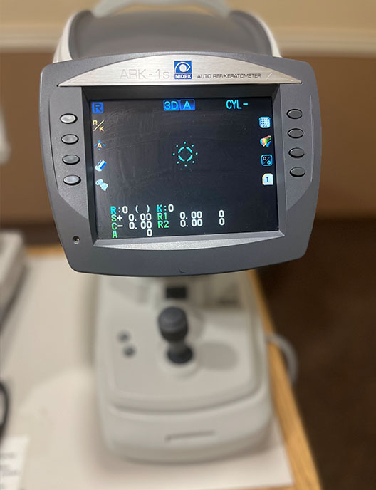 The image shows a piece of medical equipment, specifically an ultrasound machine with a screen displaying what appears to be an ultrasound image, situated on a table in a room that looks like a medical or diagnostic setting.